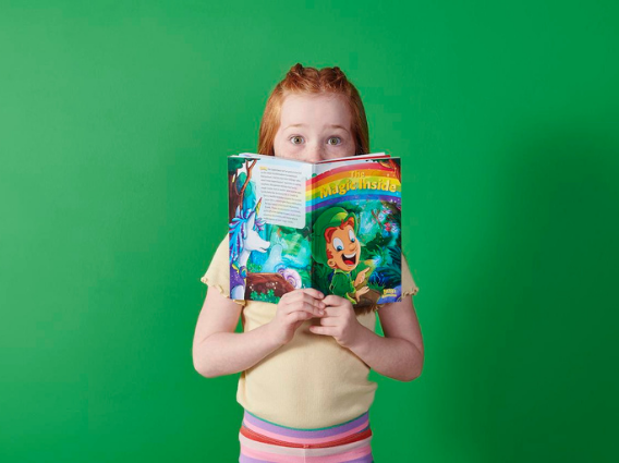 Girl peering over the book "The Magic Inside"