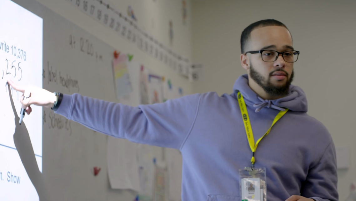 Black male teacher pointing to the whiteboard 